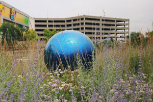 A large blue orb, the Across the Universe sculpture, outside a parking structure at Mall of America