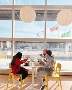 A father, daughter, and son eat breakfast with a view of the IKEA parking garage in the background