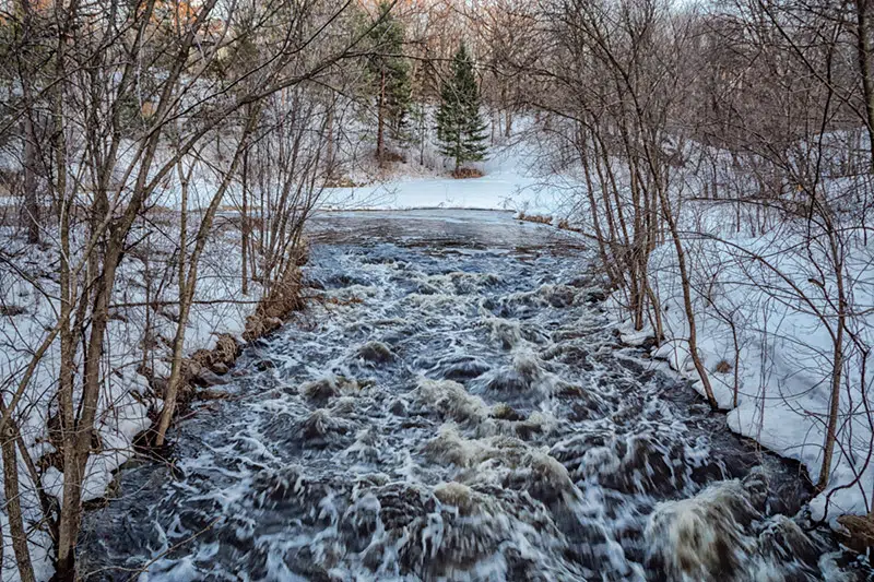 A flowing creek with snow on the banks