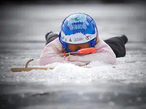 A woman watching a bobber in a lake while ice fishing