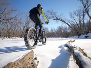 A fat tire biker rides on top of a snowy path.