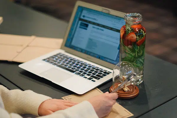 A laptop and hands taking notes during a meeting