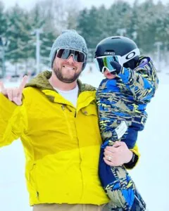 A dad holding his son on a ski slope