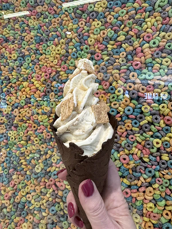 Holding an ice cream cone in front of a cereal wall