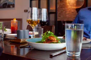 Plated dish on a table with water and two glasses of wine.