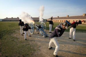 Historical re-enactors hold their ears next to cannon fire at Historic Fort Snelling