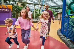 A family of 5 running through a theme park