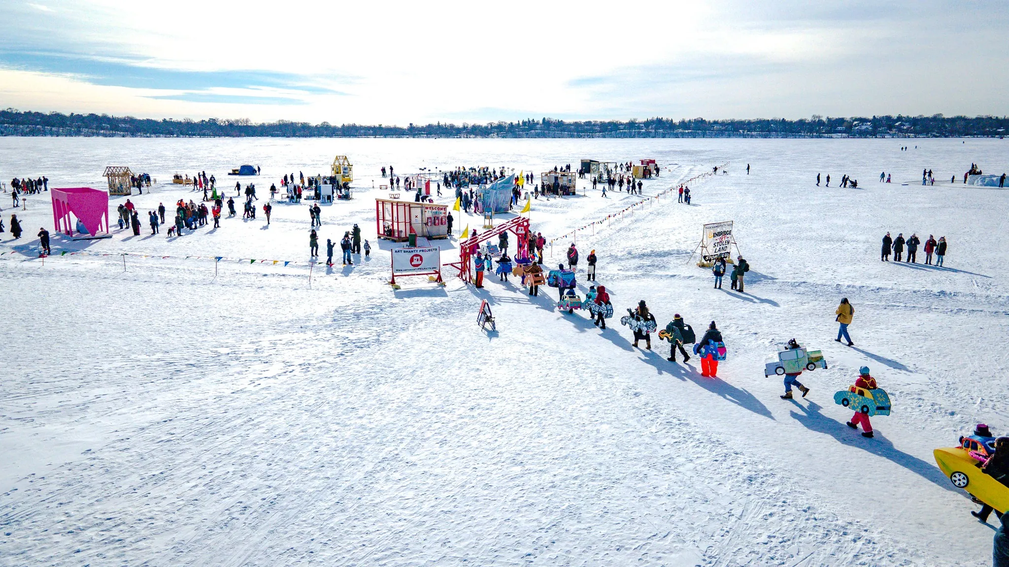 A group of people walk across a frozen lake to an art installation