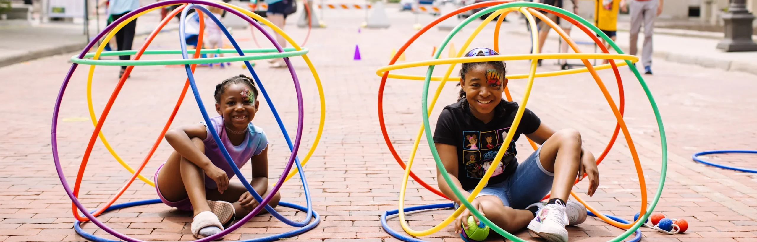 2 girls sit in colored hula hoops