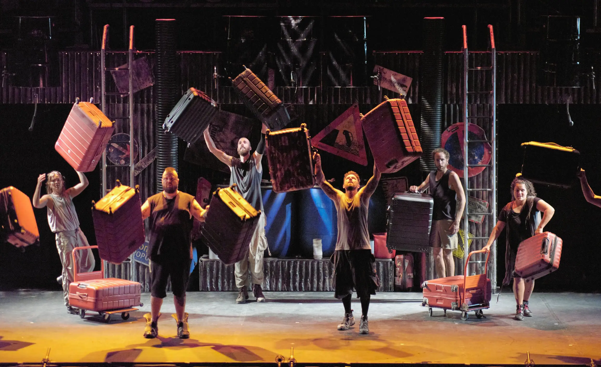 A group of dancers toss suitcases in the air