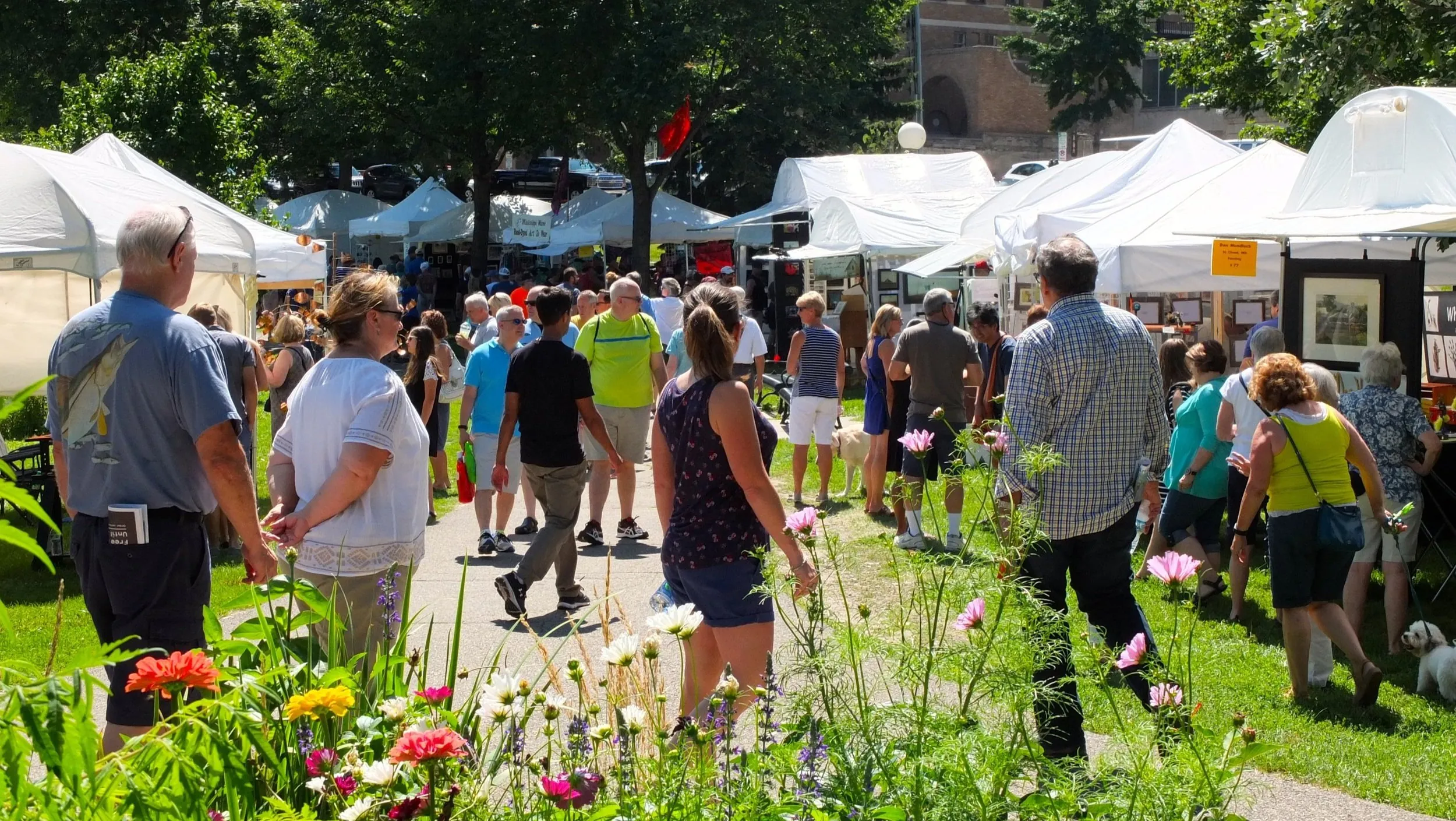 Groups of people stroll past art show booths